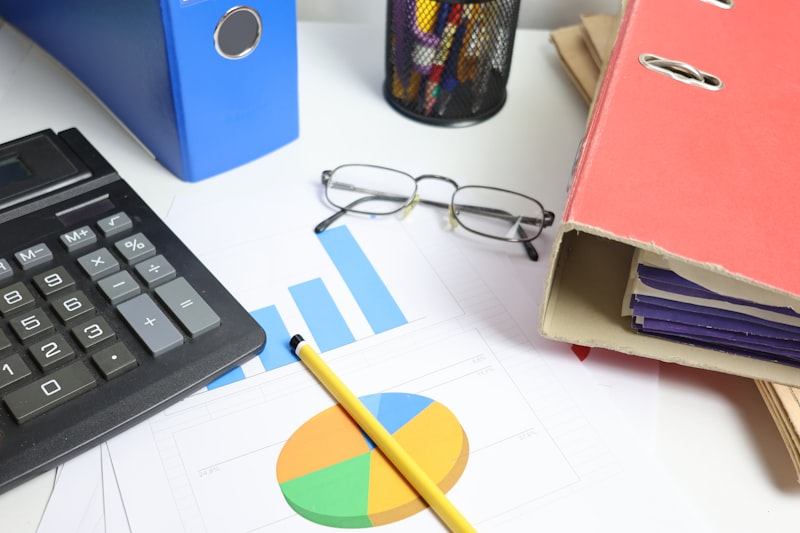 Desk with financial charts, binders, calculator and glasses for financial statement review